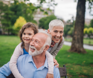 young girl hugging her grandfather with grandmother in background